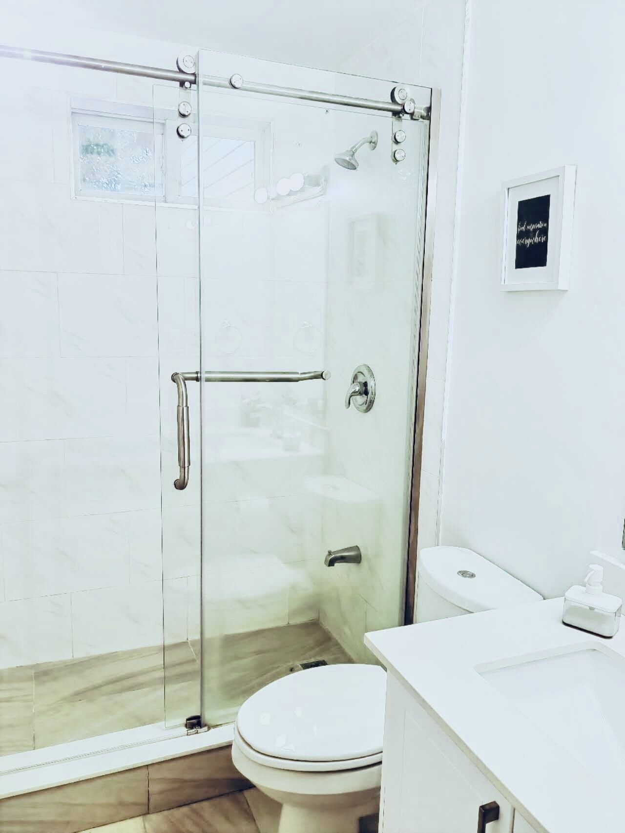 A modern bathroom with a glass-enclosed shower, a white toilet, and a white sink.