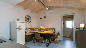 Eine kleine Küche mit Kühlschrank, einem Holztisch mit Stühlen und einer Decke mit freiliegenden Balken.