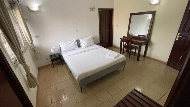 Una habitación de hotel con cama, escritorio, silla, espejo y puerta.