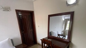 Una habitación de hotel con una cama, un escritorio y un espejo grande.
