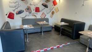 Un interior moderno con zonas de estar, una pared con ilustraciones de comida y un piso de baldosas limpio.