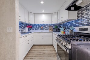 Una cocina moderna con armarios blancos, un salpicadero de azulejos azules y una estufa de acero inoxidable.