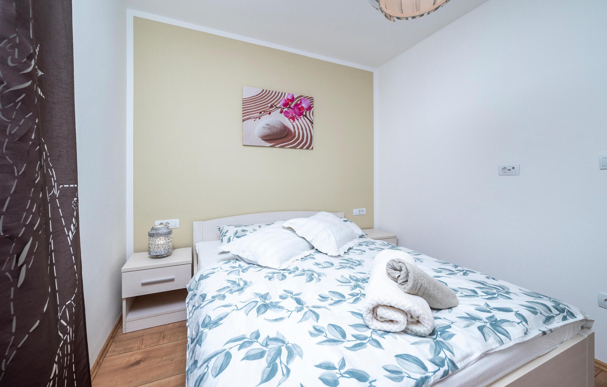 A bedroom with a bed, nightstand, and a wall-mounted artwork.