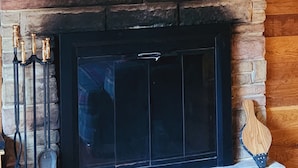 A stone fireplace with a mounted deer head above it, framed by a decorative plate.