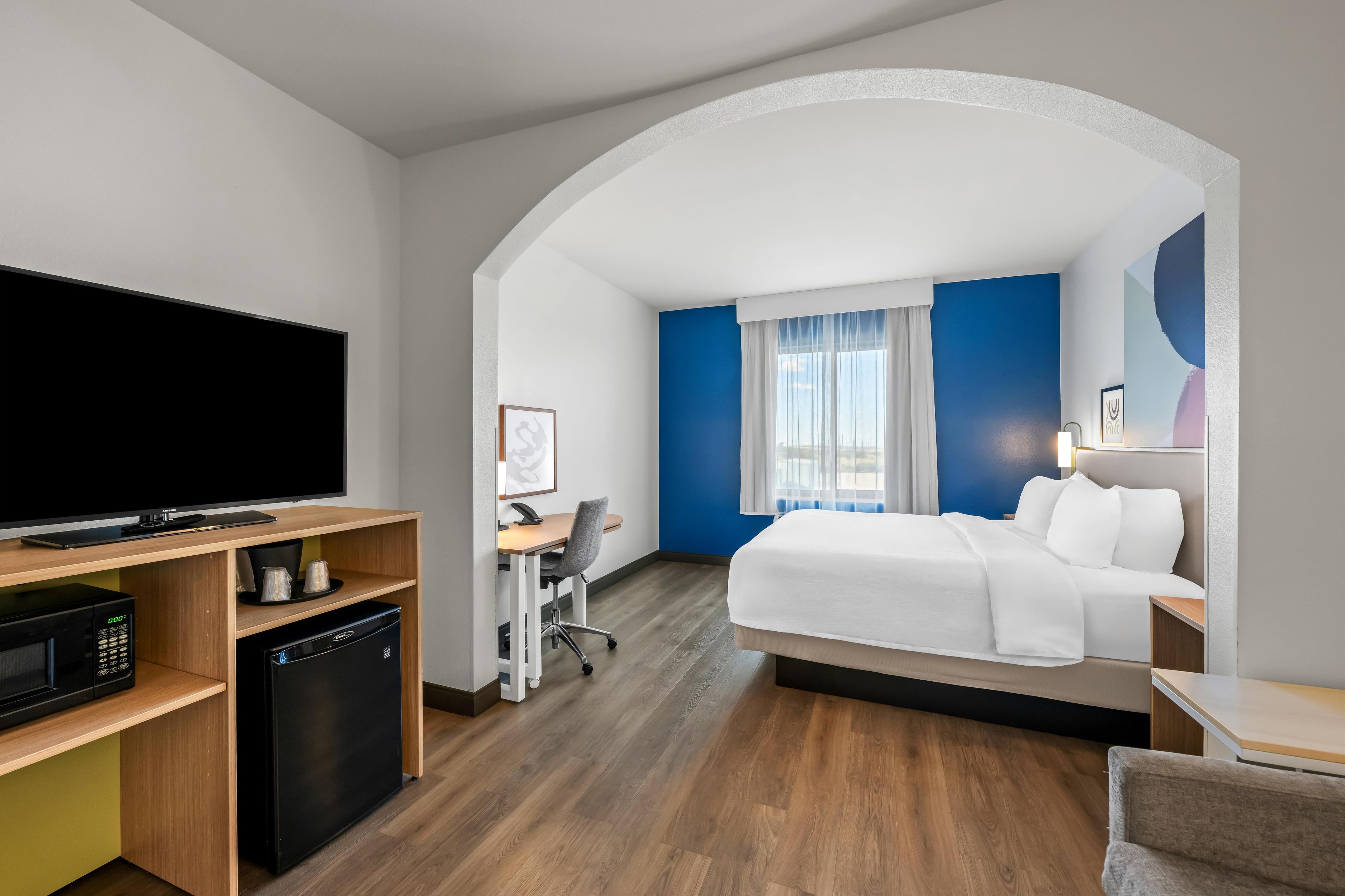 A hotel room with a bed, desk, and television.