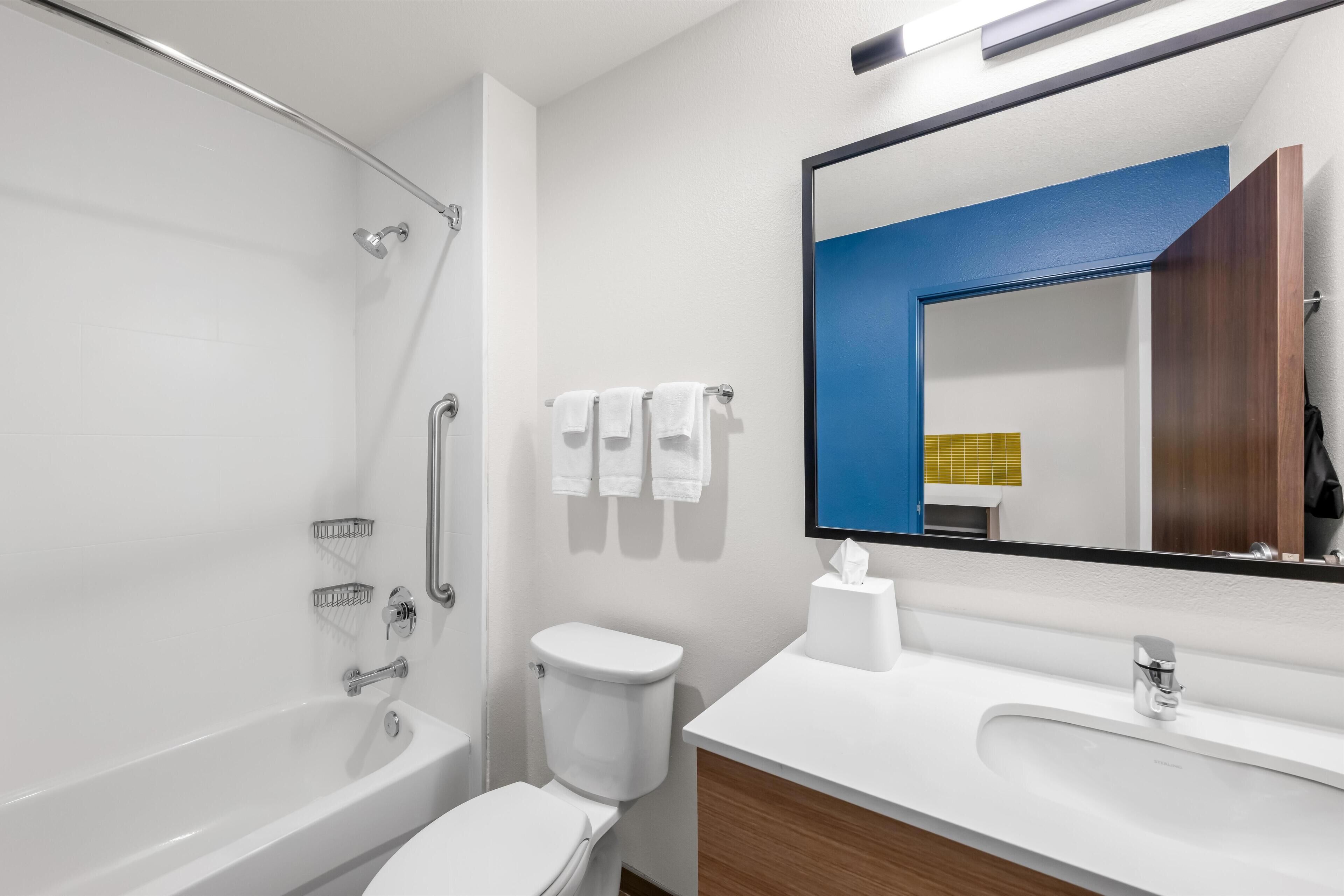 Een moderne badkamer met een badkuip, toilet en wastafel.
