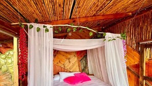 Un lit en bois avec un baldaquin, une literie blanche et un oreiller rose.