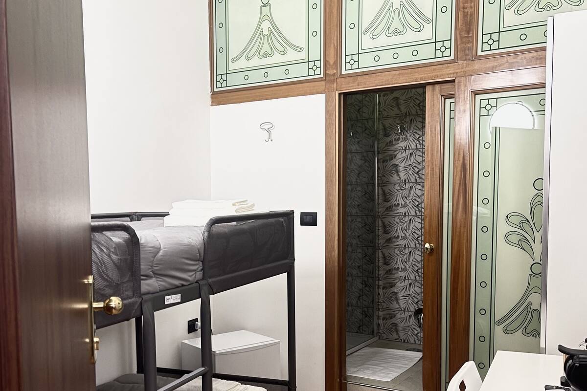 A compact room with bunk beds, a shower, and a small desk.