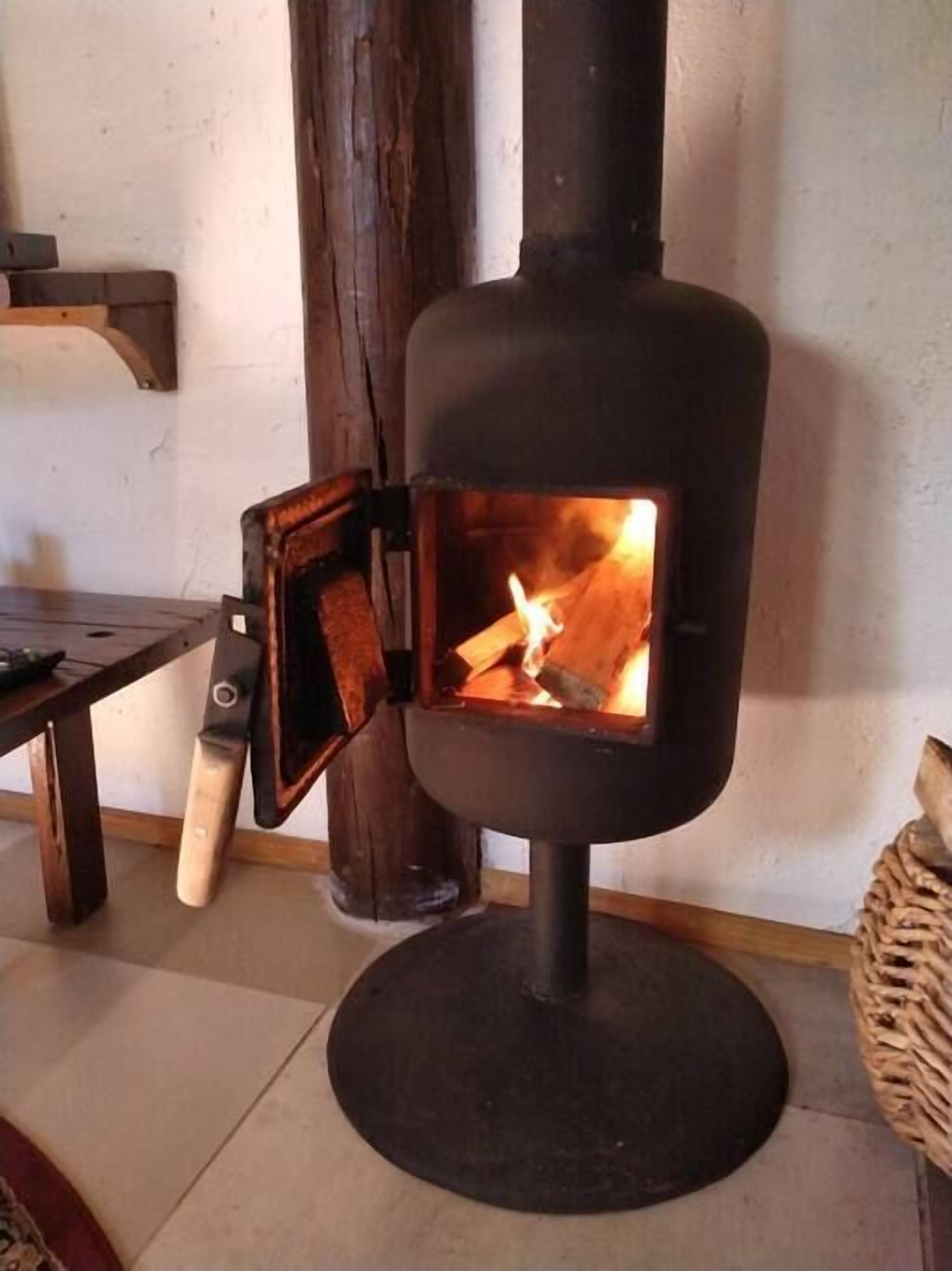 Un poêle à bois à foyer ouvert, une table en bois et un panier en osier.