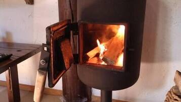 Ein Kaminofen mit offener Vorderseite, ein Holztisch und ein gewebter Korb.