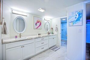 A modern bathroom with a large vanity, two round mirrors, and a blue artwork on the wall. - Stunning 180° Open Water Views (Key Colony Beach)