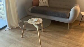 A modern living room with a grey sofa, a small round glass table, and a pendant light.