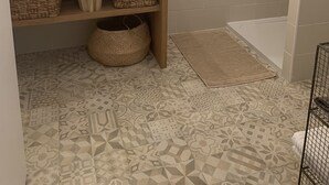 A bathroom with a white sink, a mirror, and a wooden vanity. There are patterned tiles on the floor and a small basket under the vanity.