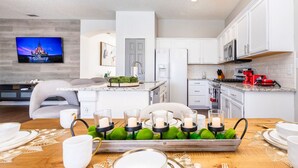 Une cuisine moderne avec des meubles blancs, un four à micro-ondes encastré et une machine à café rouge.