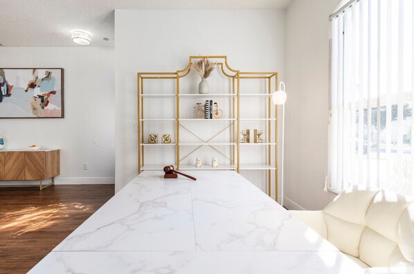 A modern living room with a marble coffee table, a gold-framed bookshelf, and a white sofa.