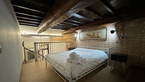 Un dormitorio con una cama, una escalera y un muro de ladrillos.