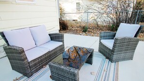 A patio area with wicker furniture, including two sofas and a coffee table, on a striped rug. - Short Drive to Friends Uni - Quaint Cottage W/ W&D (Wichita)