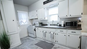 A modern kitchen with white cabinets, a microwave, and a sink. - Short Drive to Friends Uni - Quaint Cottage W/ W&D (Wichita)