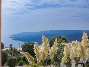 Enjoy breathtaking views of the calm sea and surrounding mountains from this serene balcony.