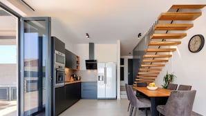 A modern kitchen with a built-in oven, a coffee machine, and a refrigerator. There is a dining area with a wooden table and chairs. - Villa MI by Interhome (Pula)