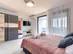 A modern bedroom with a large bed, a desk, and a TV.
