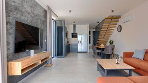 A modern living room with a large TV, a wooden coffee table, and an orange sofa. - Villa MI by Interhome (Pula)