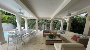 Um pátio coberto ao ar livre com piscina, área de jantar e espaço para sentar.