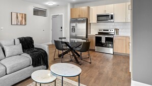 A modern living room with a grey sofa, a coffee table, and a dining area with a table and chairs. - The Platinum Suite Penthouse The Gulch  (Nashville)