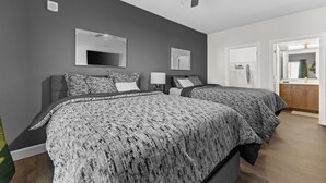 A bedroom with two beds, a ceiling fan, a TV, and a bathroom visible through an open door. - The Platinum Suite Penthouse The Gulch  (Nashville)