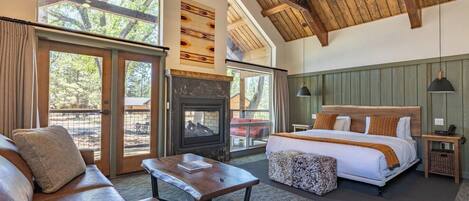 A spacious bedroom with a large bed, a wooden ceiling, and a fireplace.