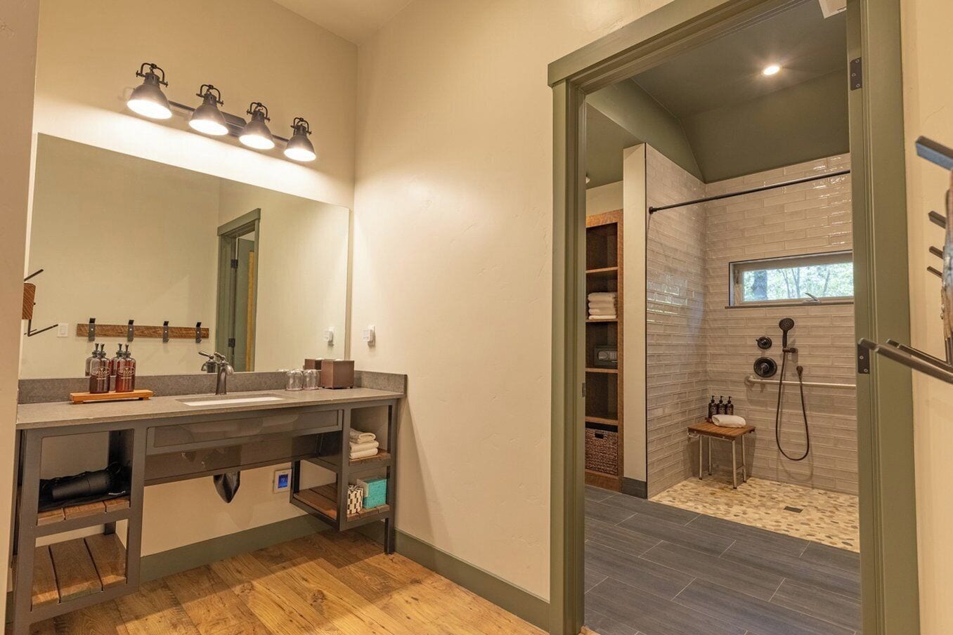 A modern bathroom with a large mirror, dual sinks, and a walk-in shower with a glass door.