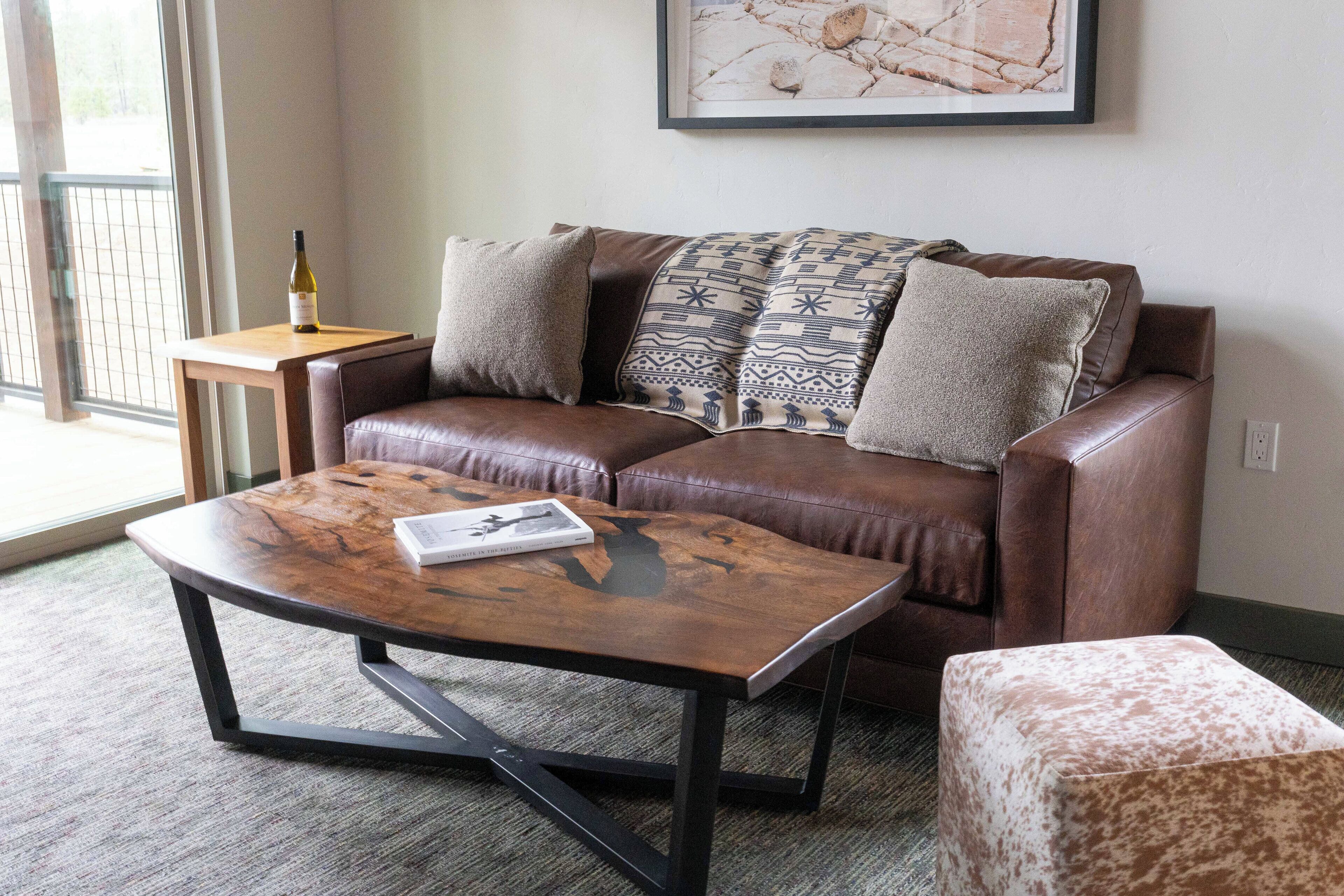 A living room with a brown leather sofa, a wooden coffee table, and a patterned throw blanket.