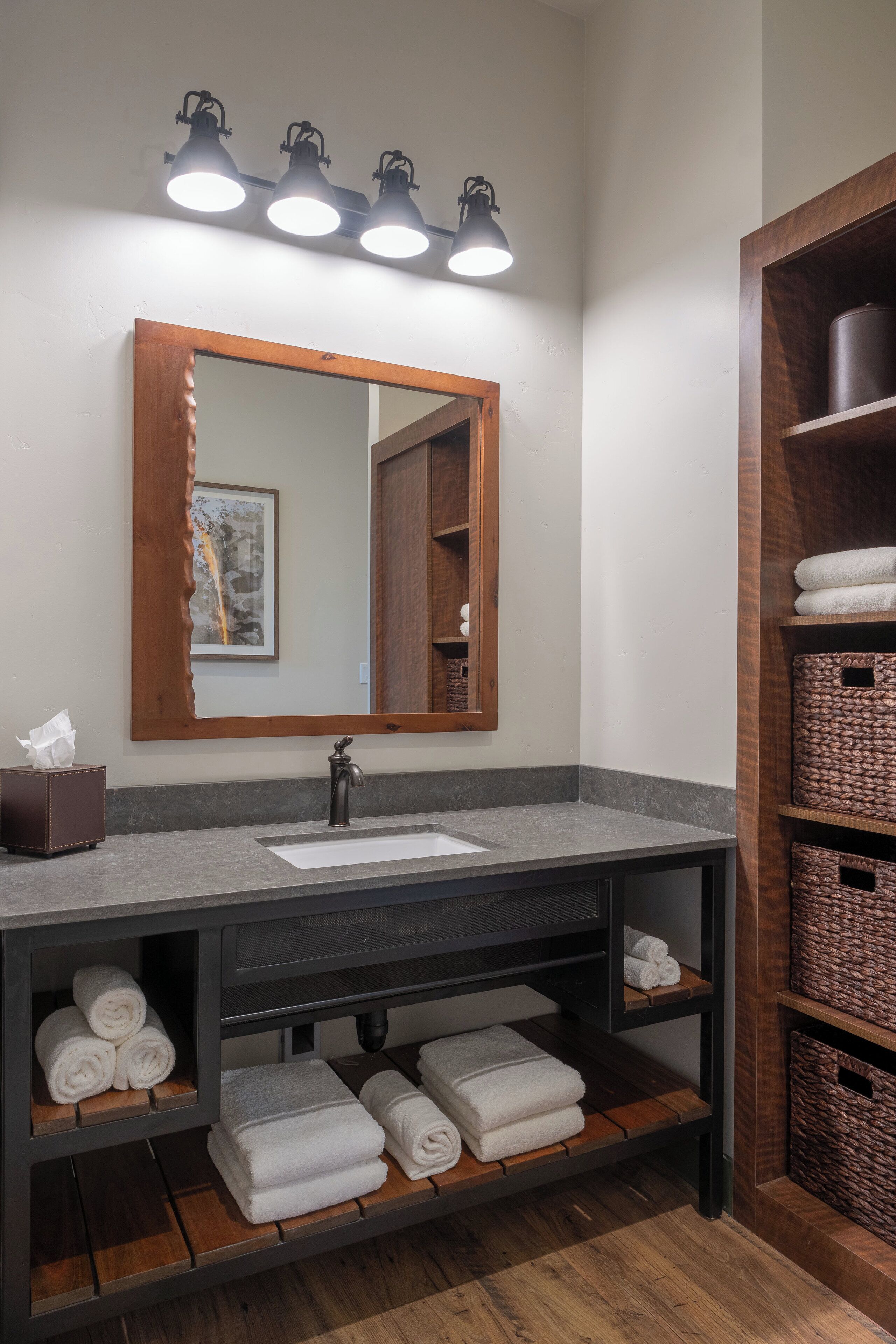 Une salle de bain avec un meuble-lavabo en bois, un grand miroir et des étagères où sont rangées les serviettes.