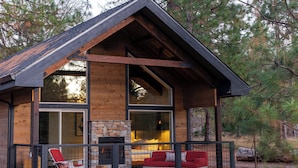 A log cabin with a balcony, a fireplace, and a stone wall.