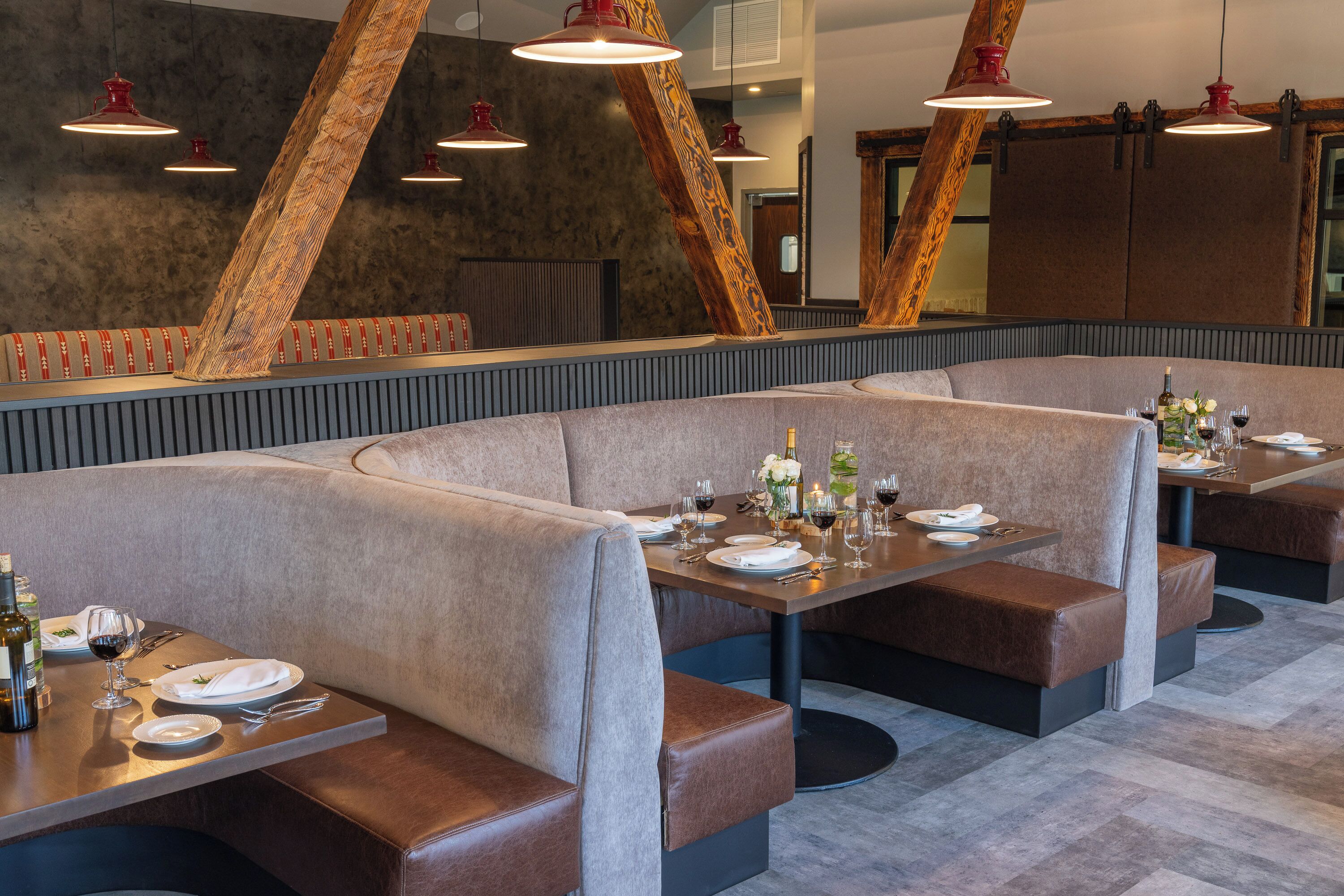 A restaurant with booth seating, tables set with wine glasses, plates, and cutlery.