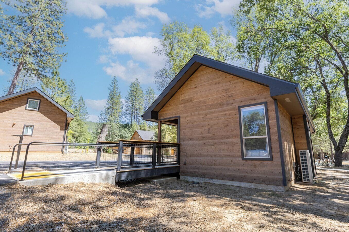 Eine Holzhütte mit Veranda, umzäunter Fläche und blauem Himmel.