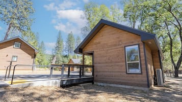 Eine Holzhütte mit Veranda, umzäunter Fläche und blauem Himmel.