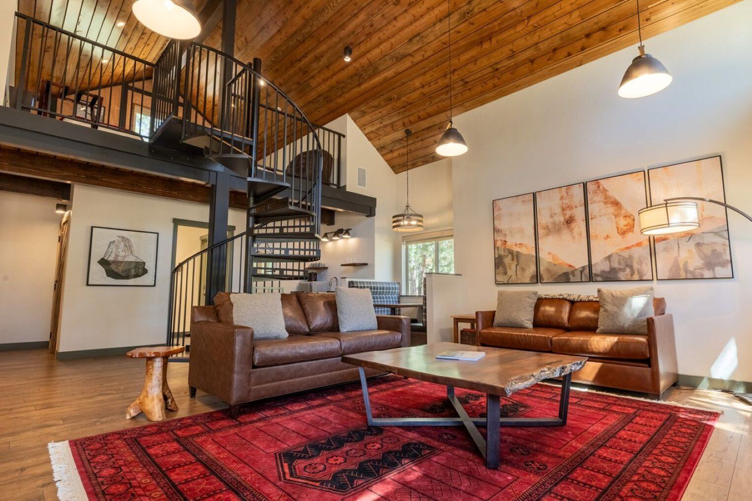 A spacious living area with a high ceiling, a staircase, and a red patterned rug.