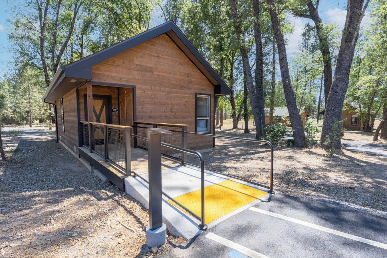 A small wooden cabin with a porch and a wheelchair-accessible ramp.