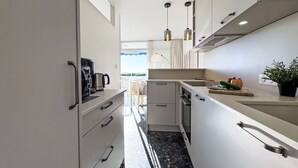A modern kitchen with white cabinets, a coffee maker, and a plant on the counter. - Le Mireille by Interhome (Le Grau du Roi)