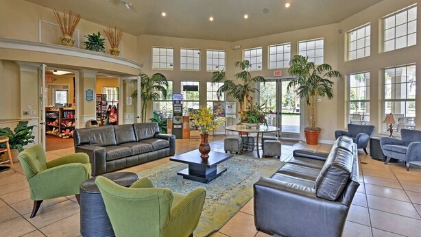 A spacious lobby with leather sofas, green armchairs, and a central coffee table. - Nature View • King Bed • Pool • 10 minutes to Disney • 5 minutes to shopping (Kissimmee)