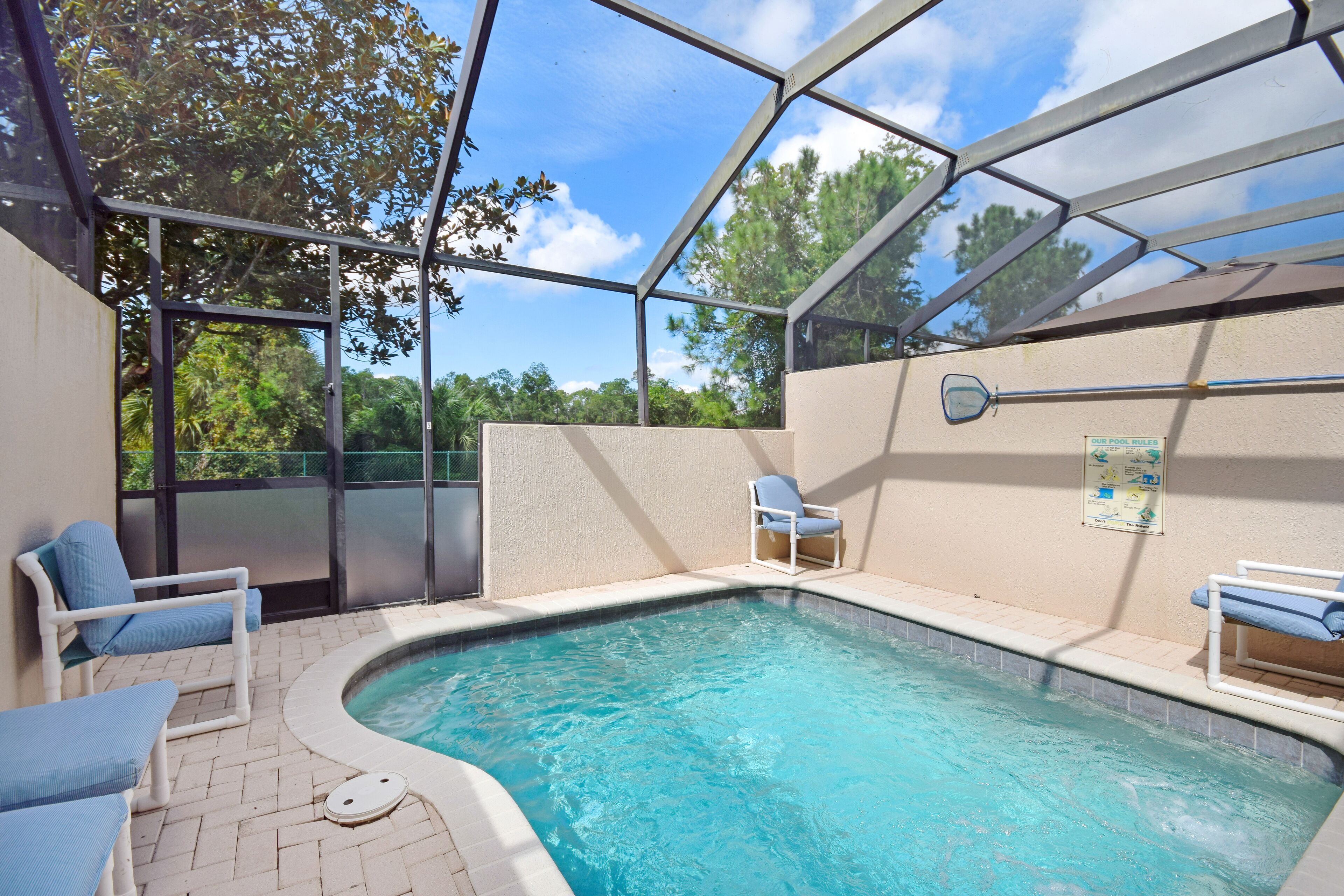 A covered swimming pool with two lounge chairs and a pool table.