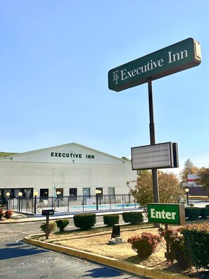 A large building labeled "Executive Inn" with a sign indicating "Enter" and a parking lot with a yellow curb.