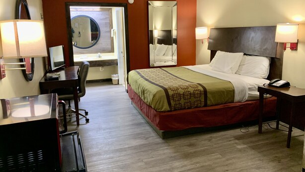 Une chambre d’hôtel avec un lit, un bureau, une chaise et un miroir.