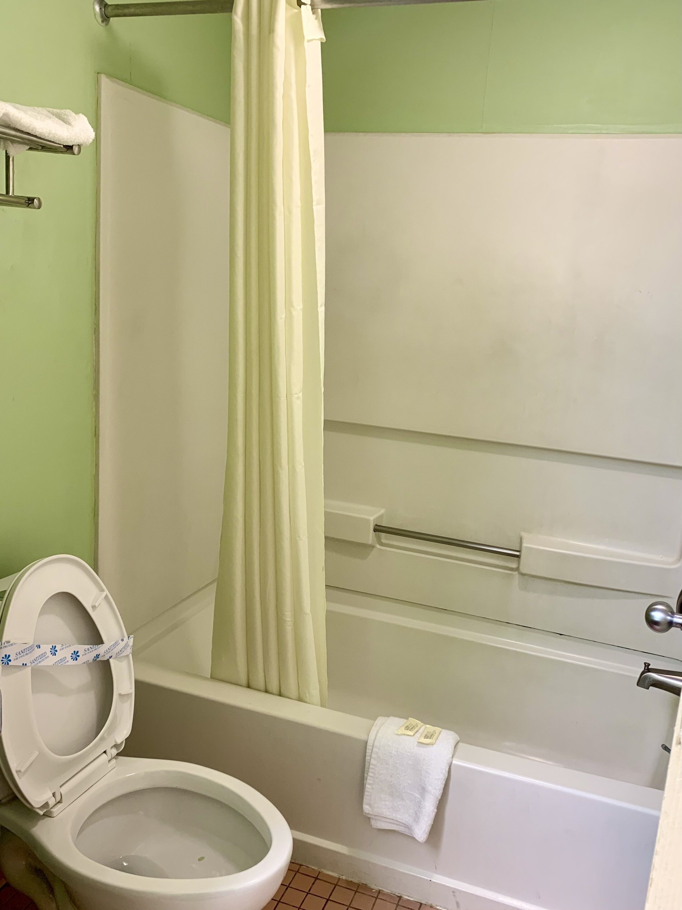 Et badeværelse med toilet, badekar og bruseforhæng.