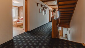 Ein Flur mit gemustertem Teppich, Holzwänden und einer Treppe.