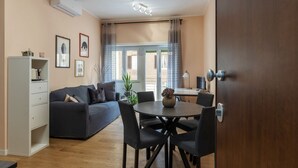 Una sala de estar moderna con un sofá, una mesa de comedor, sillas, un mueble y una puerta.