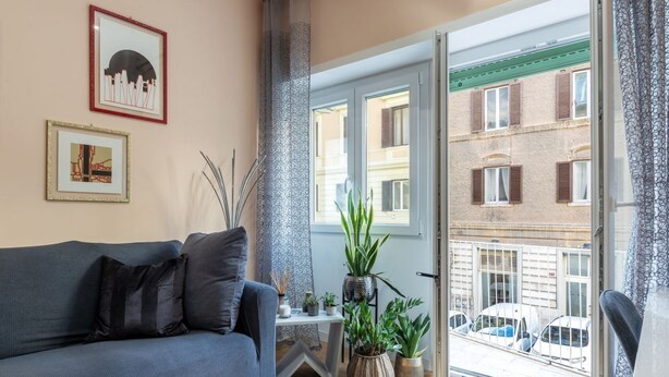 Una sala de estar con sofá, plantas en macetas y cuadros en la pared.