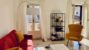 A living room with a red sofa, a yellow armchair, a black bookshelf, and a white coffee table. - GuestHost - The Design Pasta Apartment (Roma)