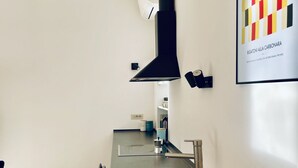 A modern kitchen with stainless steel appliances, a black range hood, and a sink. - GuestHost - The Design Pasta Apartment (Roma)